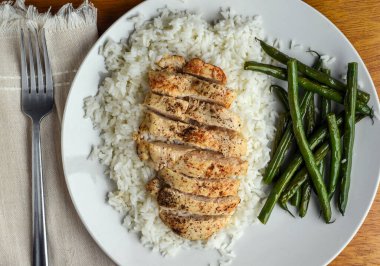  Dilimlenmiş tavuk göğsü ve sotelenmiş yeşil fasulye ile servis edilen beyaz pirinç.