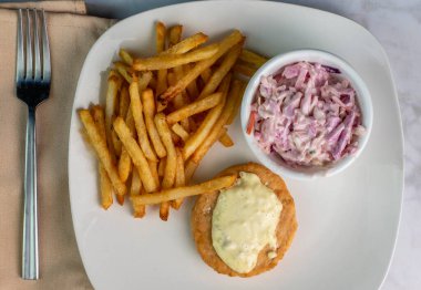 Somon burger üstü, tarter soslu patates kızartması ve lahana salatasıyla servis ediliyor.,