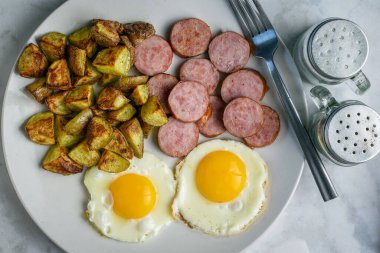 Kızarmış yumurta, yanında sosis ve patates kızartması.