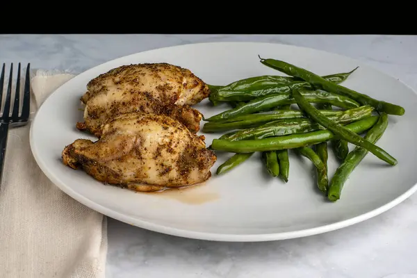 taze fasulyeyle servis edilen sulu fırında tavuk butları., 