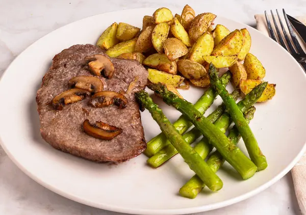 steak with mushrooms served with asparagus and potato wedges