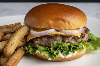 Peynirli ve soğanlı hindi burger üstü brokoli kızartmasıyla servis edilen çörekli çörek.,