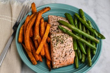 Sotelenmiş yeşil fasulye ve patates kızartması ile servis edilen pasrley ve fesleğenli fırında somon.