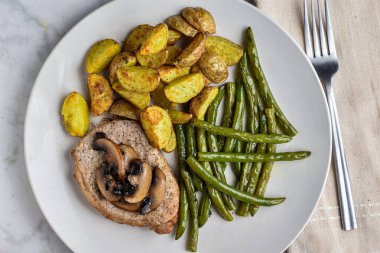 Sotelenmiş yeşil fasulye ve patates dilimleriyle servis edilen daha az domuz pirzolası., ,