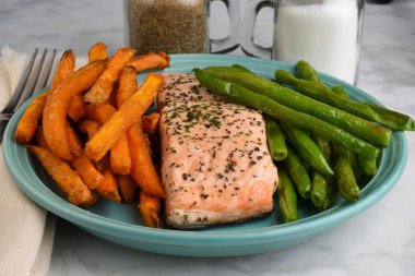 Sotelenmiş yeşil fasulye ve patates kızartması ile servis edilen pasrley ve fesleğenli fırında somon.