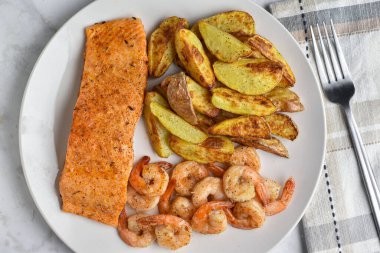 Sotelenmiş somon karides ve yanında patates dilimi ile servis edilir., 