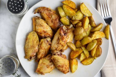 baharatlı tavuk kanadı ve yanında patates dilimleri.