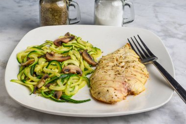 Dilimlenmiş tavuk göğsü. Kabaklı erişteyle servis ediliyor. Üstü mantarlı.,