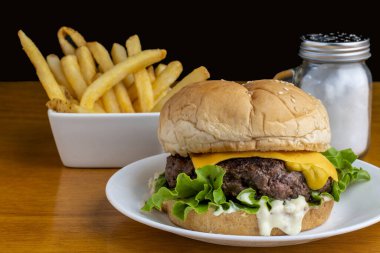 Peynirli burger üstü hardallı susamlı ekmek ve patates kızartması.