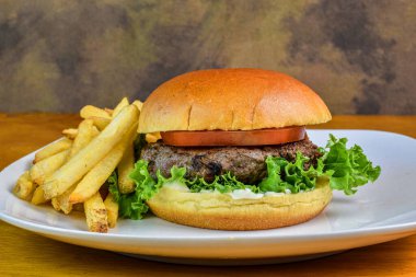 Domatesli hamburger ve patates kızartmasıyla servis edilen brioche ekmeğinde marul.