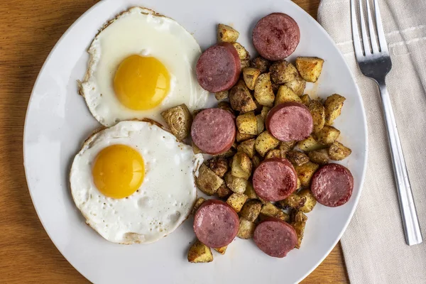 Kızarmış yumurta, yanında patates kızartması ve sosis.