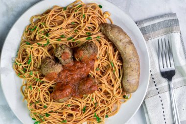 Köfteli ve tatlı İtalyan sosisli servis edilen pasrley 'li spagetti üstü..