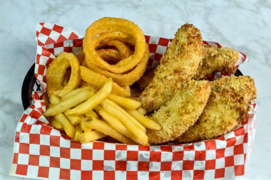  Patates kızartması ve soğan halkasıyla servis edilen çıtır tavuk kızartması.