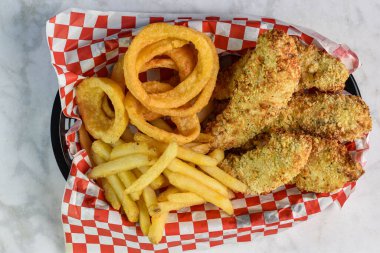 Patates kızartması ve soğan halkasıyla servis edilen çıtır tavuklar.