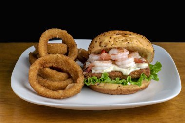 Tarter soslu balık sandviçi ve soğan halkalarıyla servis edilen karides.,