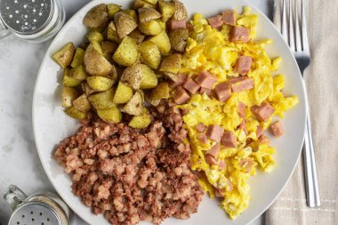 Çırpılmış yumurta, doğranmış konserve jambon, yanında sığır eti ve patates kızartması.