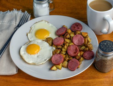Kızarmış yumurta, yanında patates kızartması ve sosis.