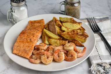 Baharatlı somon karides ve patatesle servis edilir.