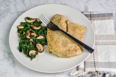 Fırında mezgit ile servis edilen ıspanak ve mantar sote.