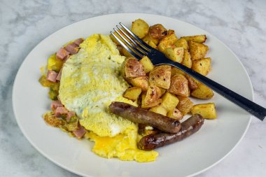 Spam Western omleti yanında patates kızartması ve kahvaltı sosisi..