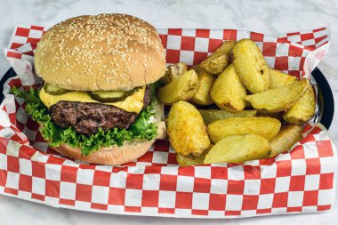 Peynirli burger üstü turşulu susamlı ekmek ve patates dilimleri.
