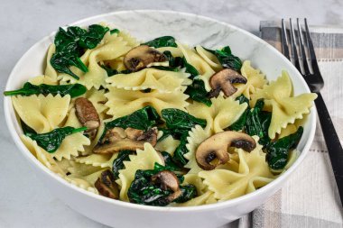 sotelenmiş sardalya ve mantarla servis edilen farfalle makarna., 