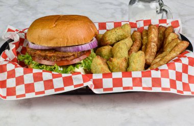 Vejetaryen burger, sebzeli patates ve brokoli ile servis edilir.