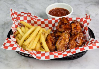 yanında patates kızartmasıyla servis edilen kanatlı babacue.