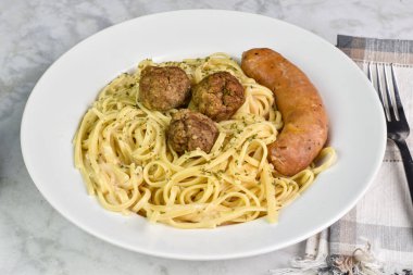 İtalyan sosisi ve köfte ile servis edilen alfredo soslu linguine..