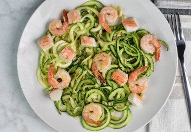 Sotelenmiş karides ve yengeç parçalarıyla servis edilen kabaklı erişte., 