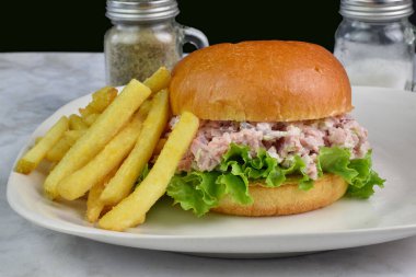 Çöreğin üzerine konserve jambon salatası yanında patates kızartması servis edildi.,