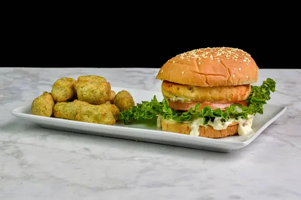 salmon  burger  on a sesame bun served with veggie fries