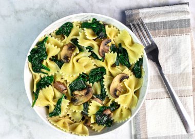 Bir kase sotelenmiş ıspanak ve mantarlı makarna.,