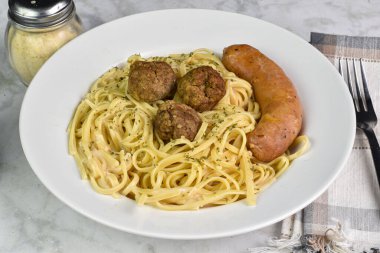 İtalyan sosisi ve köfte ile servis edilen alfredo soslu linguine..