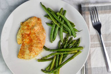 Baharatlı tavuk göğsü sotelenmiş yeşil fasulye ve kuşkonmazla servis edilir.,