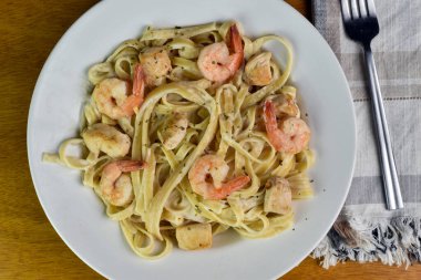 Sotelenmiş karides ve tavukla servis edilen linguine alfredo.