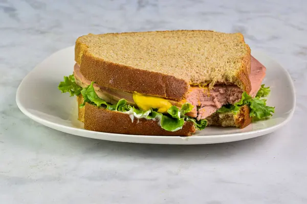stock image bologna sandwich  top with mustard   on wheat bread