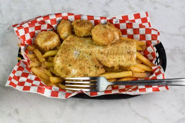 Fırında mezgit, deniz tarağı ve patates kızartmasıyla servis edilir.