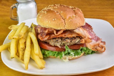 Pastırmalı hamburger, marul ve domates ve susamlı çörek.