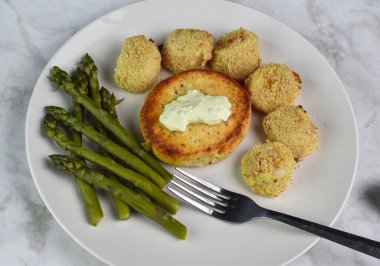 salmon burger top with tarter sauce served with  asparagus and baked scallops clipart