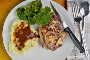 soğanlı kemiksiz biftek ve patates püresiyle servis edilen mantarlar.