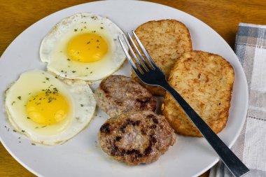 İki yumurta üstü maydanozlu patates kızartması ve sosisli börek.
