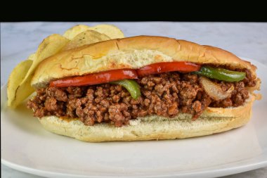   Soğanlı, biberli ve yanında patates kızartması olan sosisli sandviç.