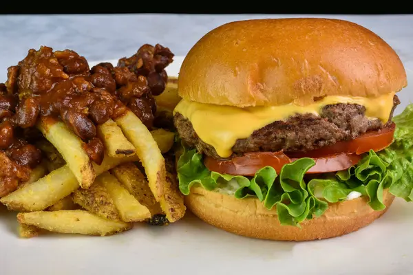 Broiche ekmeğinde peynirli burger, acılı patates kızartması.