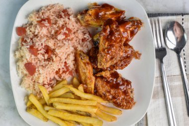 Pirinçli tavuk kanadı ve yanında patates kızartması ile domates.