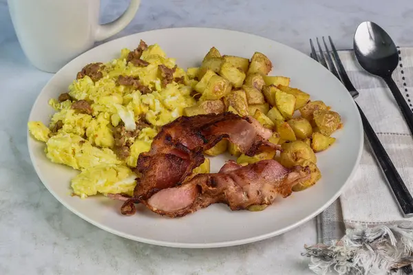 Domuz pastırması ve kızarmış patatesle servis edilmiş sosisli omlet.,