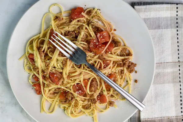 Linquine sosis ve doğranmış domates sunar..
