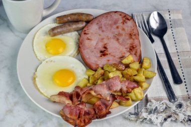 Domuz pastırmalı sahanda yumurta, sosis ve yanında patates kızartması.,