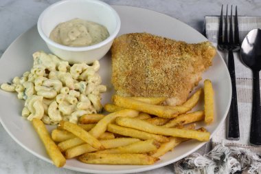 Patates kızartması ve makarna salatasıyla servis edilen mezgit balığı.