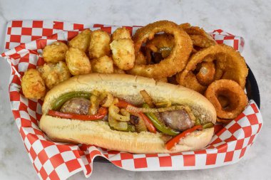 Soğan ve biberli tatlı İtalyan sosisli sandviç, soğan halkaları ve patates kroket ile servis edilir.,